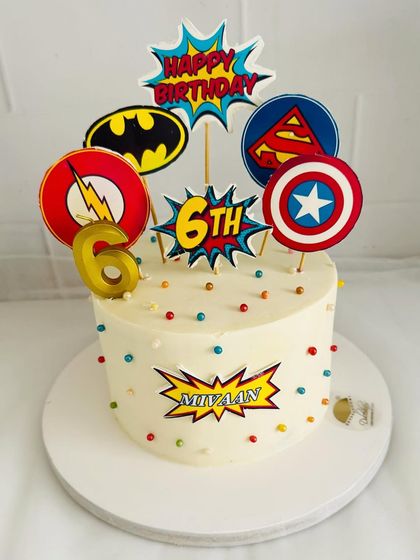 A fun superhero collage cake featuring logos from Batman, Superman, The Flash, and Captain America.