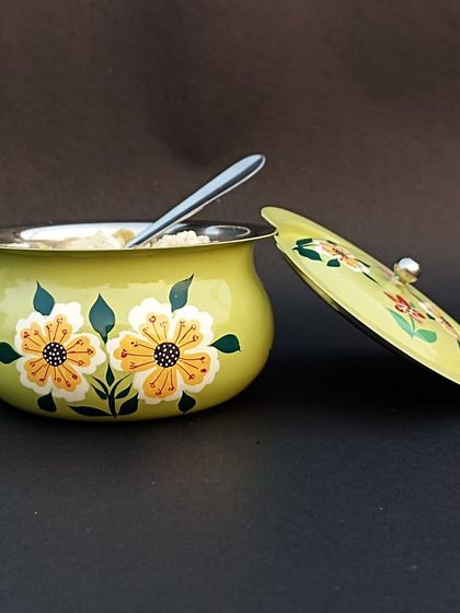 A charming hand-painted yellow pot with a lid, perfect for storing sugar or spices.