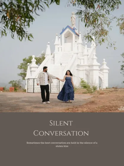 A lovely wide shot of a couple in front of a classic white Goan church, capturing a moment of quiet conversation and connection.