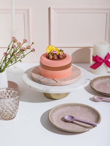 A lovely pink entremet topped with chocolate details and a dried orange slice, ready to fulfil all your cravings.