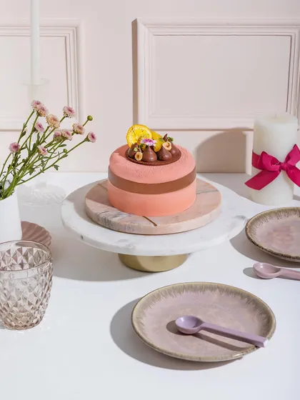 A lovely pink entremet topped with chocolate details and a dried orange slice, ready to fulfil all your cravings.