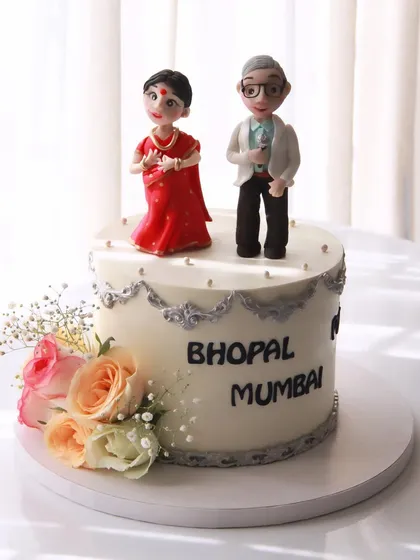 This 25th anniversary cake tells a beautiful love story. The handcrafted toppers represent the couple, who met through their shared love of singing and dancing, and the cake features the names of the cities they've lived in together.