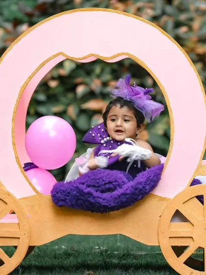 The birthday girl enjoying a moment in her princess carriage during an outdoor party.
