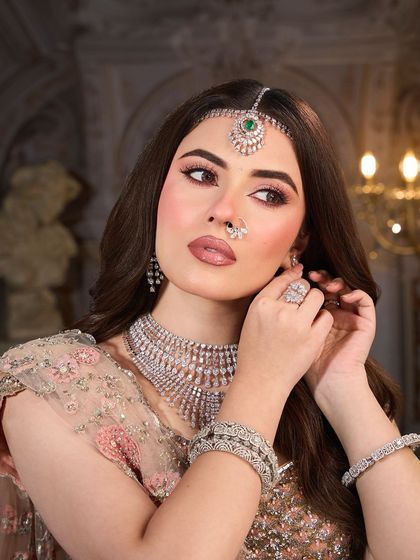 The final touches. This shot captures the elegance of the look, with the focus on the beautiful diamond jewelry and the soft, radiant makeup.