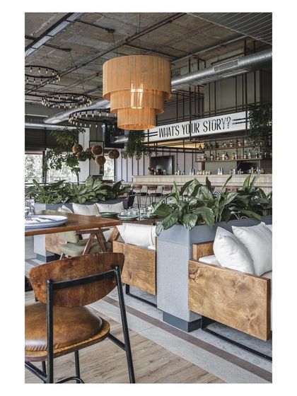 The combination of plush sofa seating and wooden chairs offers a variety of comfort levels. The large planters act as natural dividers, creating distinct zones within the open layout.