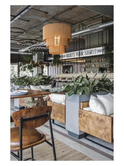 The combination of plush sofa seating and wooden chairs offers a variety of comfort levels. The large planters act as natural dividers, creating distinct zones within the open layout.