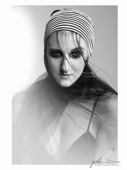An artistic black and white portrait with a creative use of sheer fabric and motion blur, creating a high-fashion, ethereal look. This highlights my ability to create timeless and emotive B&W images.