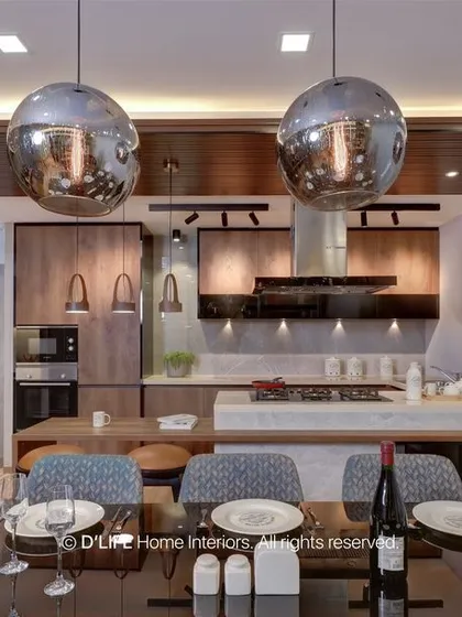 An open-plan dining area that flows into the kitchen, featuring large metallic globe pendant lights that serve as a dramatic focal point over the dining table.