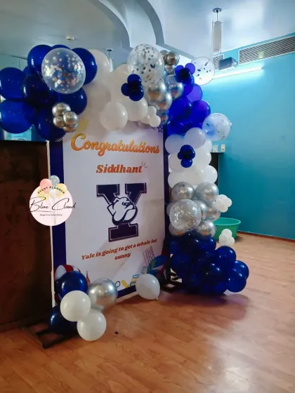 A 'Congratulations' party setup for a university acceptance, with a custom banner and a blue, white, and silver balloon garland.