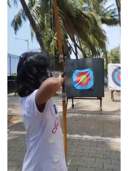 A young girl aims her shot at our outdoor range, with the beautiful palm trees in the background.