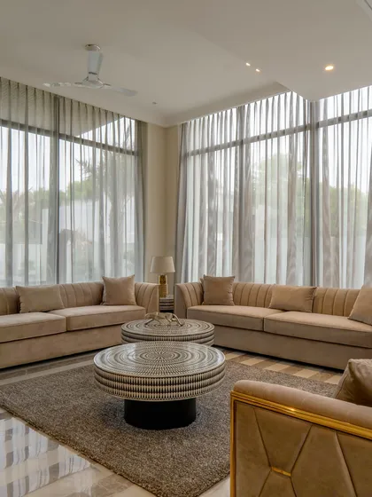 The full view of this serene drawing room, with its comfortable sofas and large windows. The design prioritizes natural light and a connection to the outdoors, making the space feel both expansive and intimate.