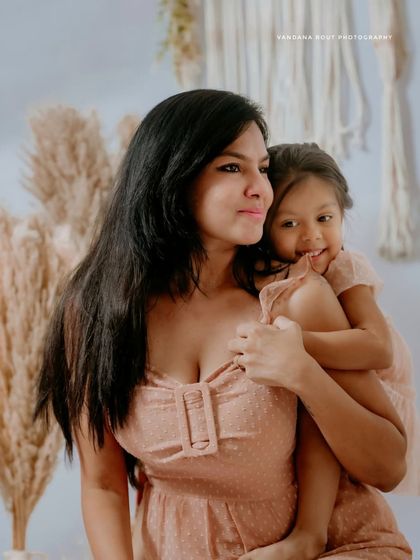 A candid moment from a boho-themed Mom & Me studio shoot. The mother looks away while her daughter cuddles close, creating a natural and artistic portrait.