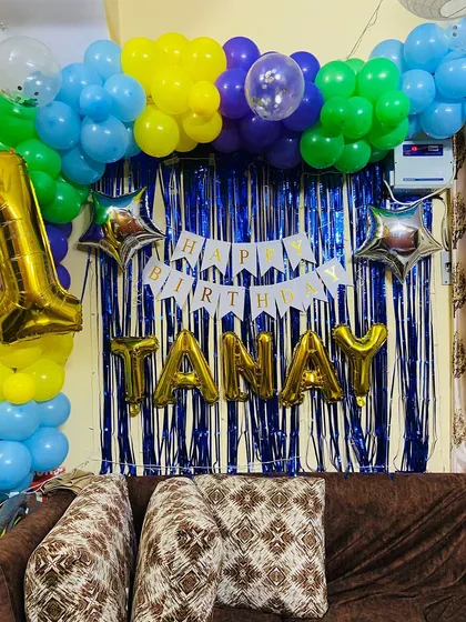A different angle of the colorful first birthday decor, showing how the balloon arch frames the personalized backdrop.