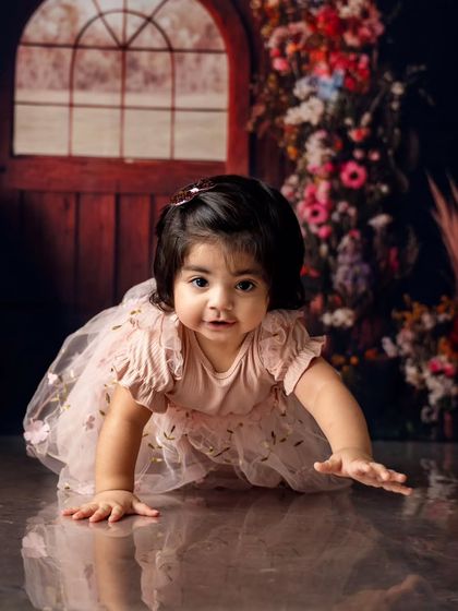 Crawling into her first birthday celebration. The floral archway and rustic door create a magical entrance for this little one's special day.