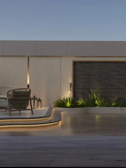 The same terrace view at dusk, where the integrated LED lighting along the curved steps and planters transforms the space. This thoughtful landscape lighting design creates a warm, inviting, and functional outdoor room for evening relaxation.