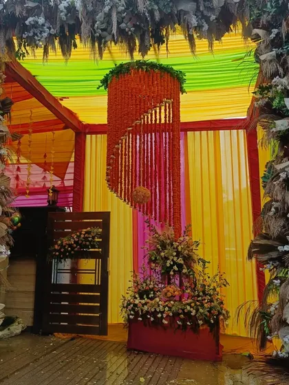 This is a very colorful entrance I designed for a Mehandi party. It features a tented structure with multi-colored drapes, a hanging floral chandelier made of marigolds, and pampas grass for a modern fusion look.