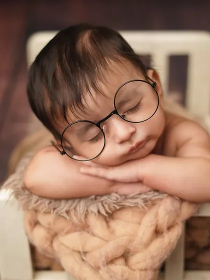 A close-up on our little reader's face. The oversized glasses add a touch of adorable comedy to this creative newborn portrait.