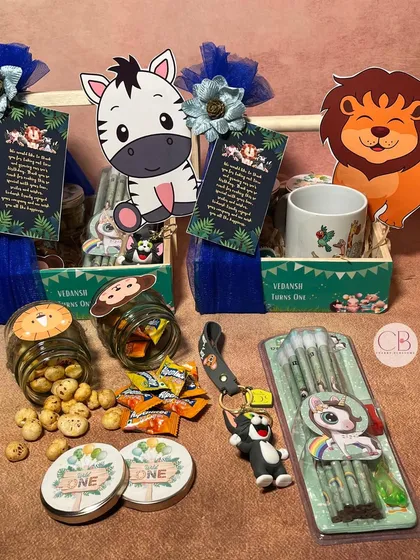 A closer look at the fun treasures inside our jungle-themed return gift hampers. We included a charming mug, tasty foxnuts, candies, playful pencils, and adorable keychains, perfect for thanking little guests.