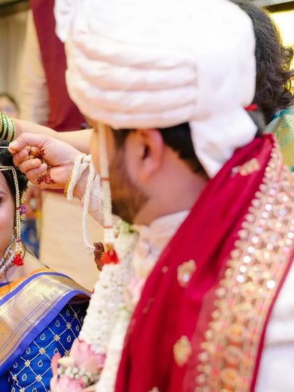 A close-up of a sacred ritual, where a family member blesses the couple, with the bride's hopeful gaze fixed on her groom.