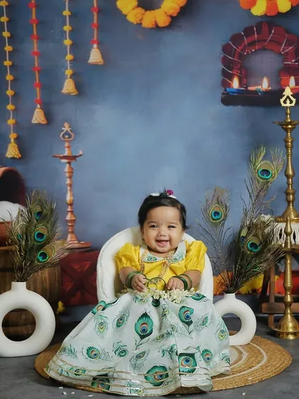 A beautiful little girl dressed in a peacock-feather-themed skirt for our Janmashtami shoot. Her smile truly lights up the photo.