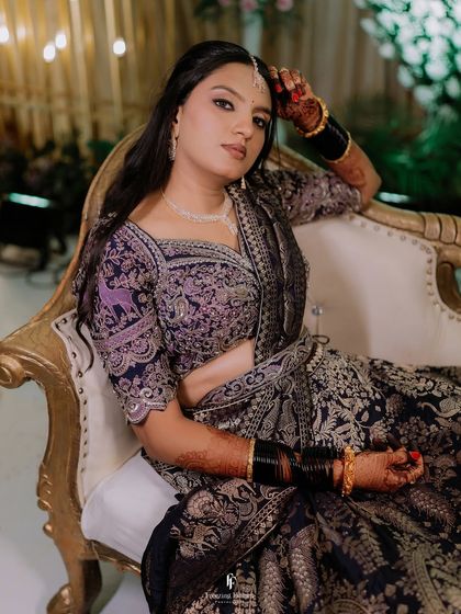 A regal portrait of the bride seated on a gilded chair, her intricate lehenga and confident pose creating a powerful image.