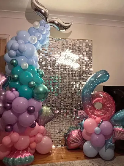 An intricate mermaid-themed balloon sculpture for a 6th birthday, featuring a shimmer wall and a large foil number balloon.