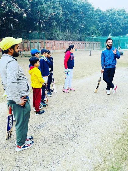 A coach addresses a group of young players during an evening session. These team talks are important for discussing strategy, setting goals, and motivating the players.