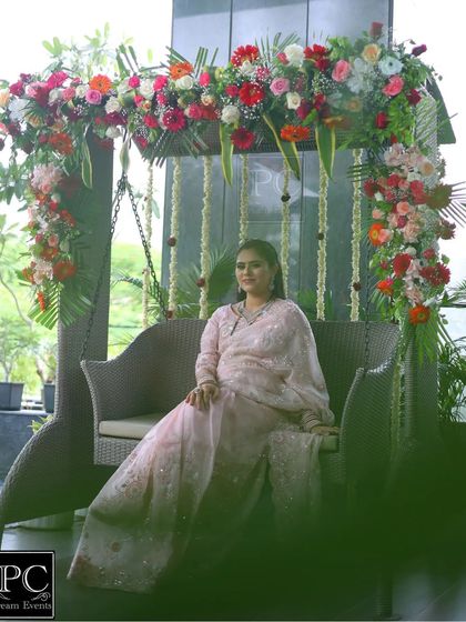 The mom-to-be enjoying her special day on the beautifully decorated floral swing. This setup provides a comfortable and picturesque spot for her to relax and greet guests.