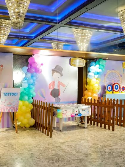 A wide view of the activity area, featuring various game stalls and a tattoo station against themed backdrops.