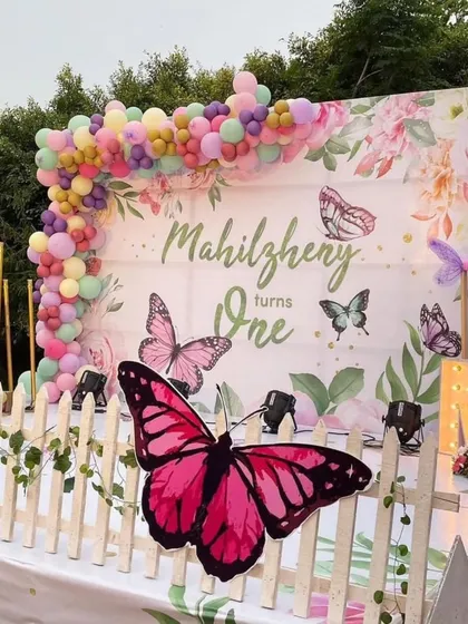 This beautiful butterfly-themed first birthday setup features a custom floral backdrop, a pastel balloon garland, and large, eye-catching butterfly cutouts for a magical garden party feel.