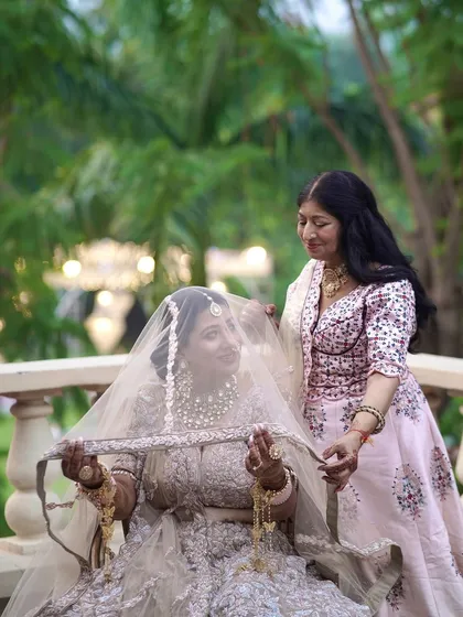 A mother or sister helps the bride with her veil, a touching and intimate moment.