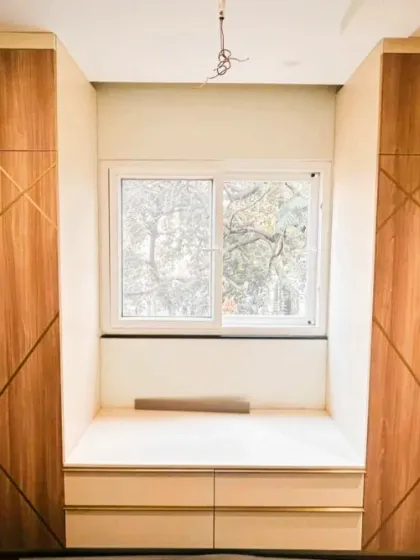 We love creating multi-functional spaces. Here, we designed twin wardrobes around a window, building a cozy bay window seat with built-in storage drawers below, turning a simple wall into a relaxing reading nook.