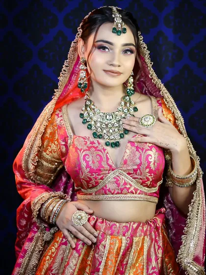Full of grace, this bride showcases a beautiful blend of pink, orange, and gold in her attire. The makeup is kept fresh and luminous to balance the richness of the outfit.
