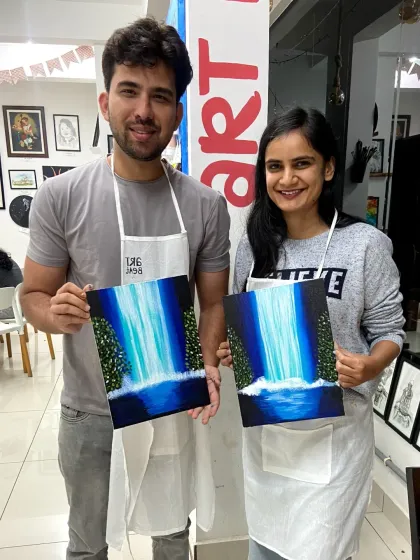 A happy couple proudly displaying the matching waterfall paintings they created together during a canvas painting session. My workshops are a popular choice for a creative and memorable date.