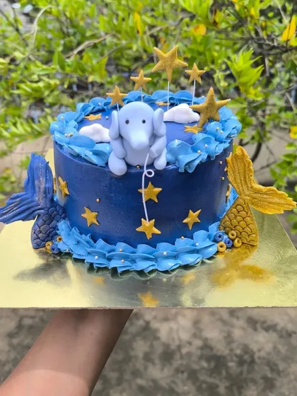 Mermaids, elephants, and galaxies. This cake brings comfort creatures and cosmic dreams to life, featuring a fondant elephant among the stars and mermaid tails diving into the cake.