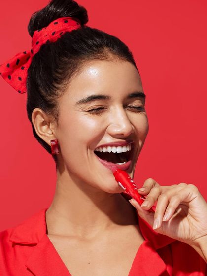 A close-up showing the simple but effective styling with a red top and matching polka-dot hair accessory, keeping the focus on the model's happy expression.
