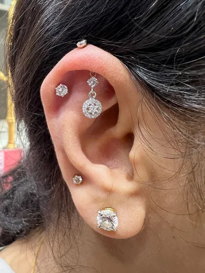 A classic and elegant ear stack. A simple solitaire stud is paired with a dangling halo piece, creating a timeless look that's perfect for any occasion.
