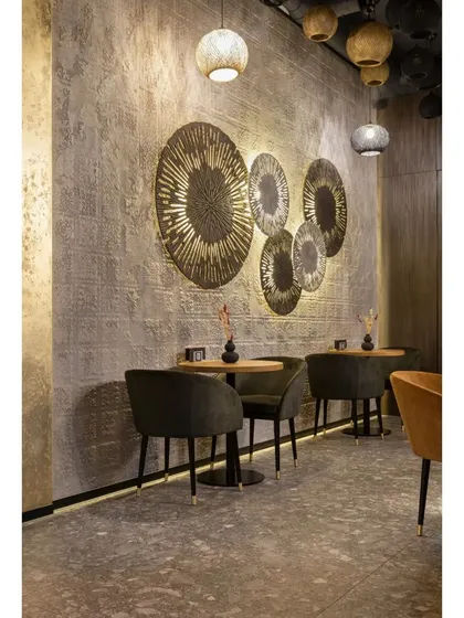 This wall features large, circular metallic art pieces that catch the light, adding a decorative and artistic touch to the cafe's interior.