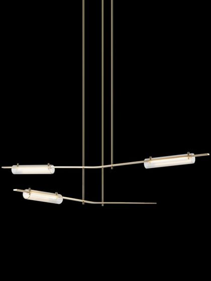 The Volant chandelier with a natural hand-rubbed brass finish and clear textured glass, offering a warmer and brighter aesthetic.