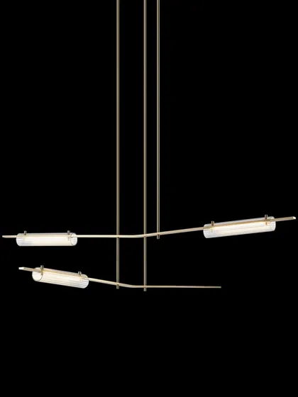 The Volant chandelier with a natural hand-rubbed brass finish and clear textured glass, offering a warmer and brighter aesthetic.