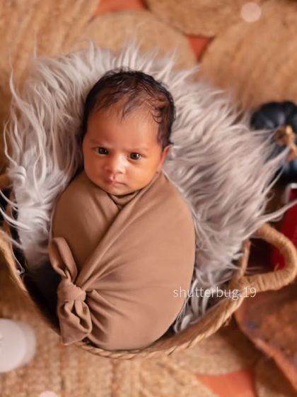 A calm and curious expression from this swaddled newborn, photographed from above in our earthy-toned boho setup.