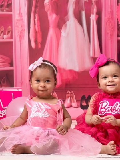 Double the fun with twin baby girls dressed as Barbie. This shot captures their adorable interaction in the fully pink, sparkly studio setup.