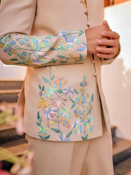 The soul of our work is in the details. This close-up reveals the delicate, multi-colored floral embroidery on one of our custom bandhgala jackets. Each thread is placed with precision by our karigars to create a design that feels both opulent and personal.