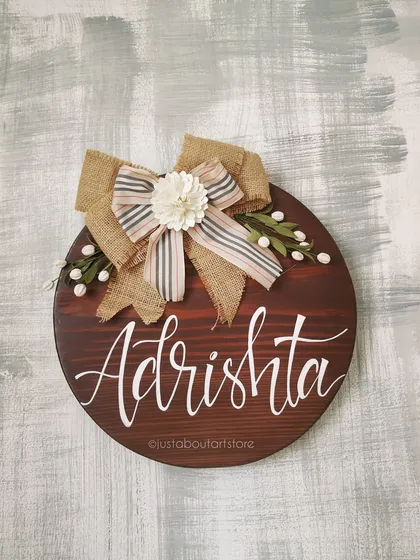 A duplicate of 216, a straight-on shot of the "Adrishta" name board, showcasing the beautiful burlap bow with its handmade flower and delicate details.