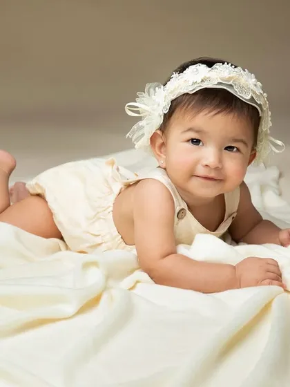 This little princess is a pro at tummy time. Her sweet smile and the soft, neutral tones of the setup create a timeless and beautiful portrait.