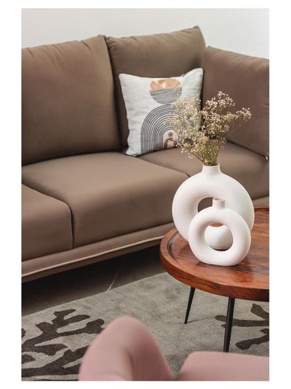 A close-up of the styling in the living room. The organic shapes of the ceramic vases and the abstract patterns on the cushion and rug add artistic flair to the neutral space.