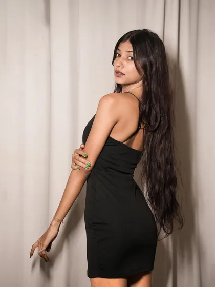 A confident pose from the back, showing off the simple lines of the black dress and the model's strong posture.