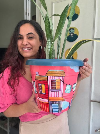 A finished city-themed planter, painted in bright pinks and reds. These make a wonderful, vibrant home for your favorite indoor plants.