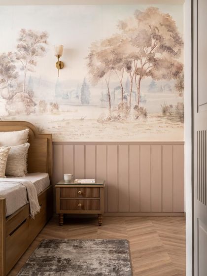 This bedroom features a stunning, soft-toned landscape mural that acts as a serene backdrop for the custom wooden bed. The paneled wainscoting adds a classic architectural detail.