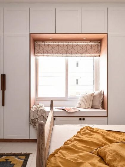 This guest bedroom wardrobe features a built-in bay window seater, a clever way to combine storage with a cozy reading nook.